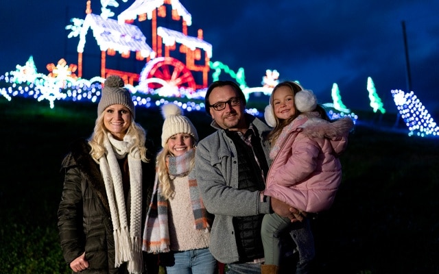 Family posing in front of Winterfest holiday lights at Old Mill