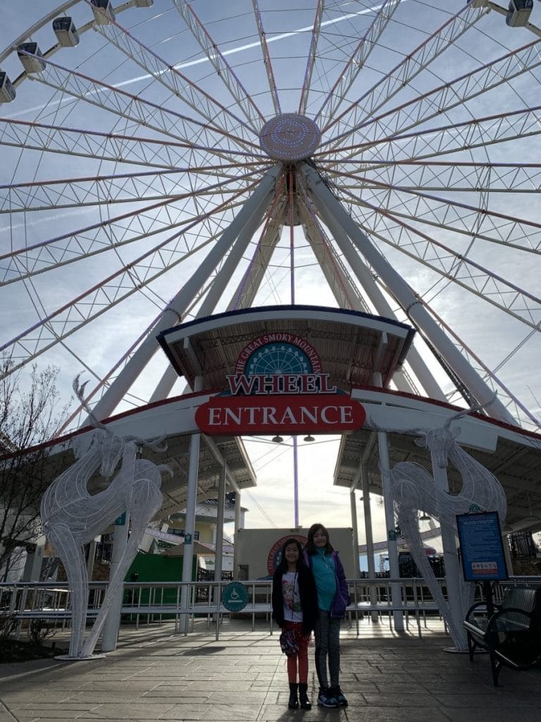 Girls posing in front of the giant Great Smoky Mountain Wheel at The Island in Pigeon Forge