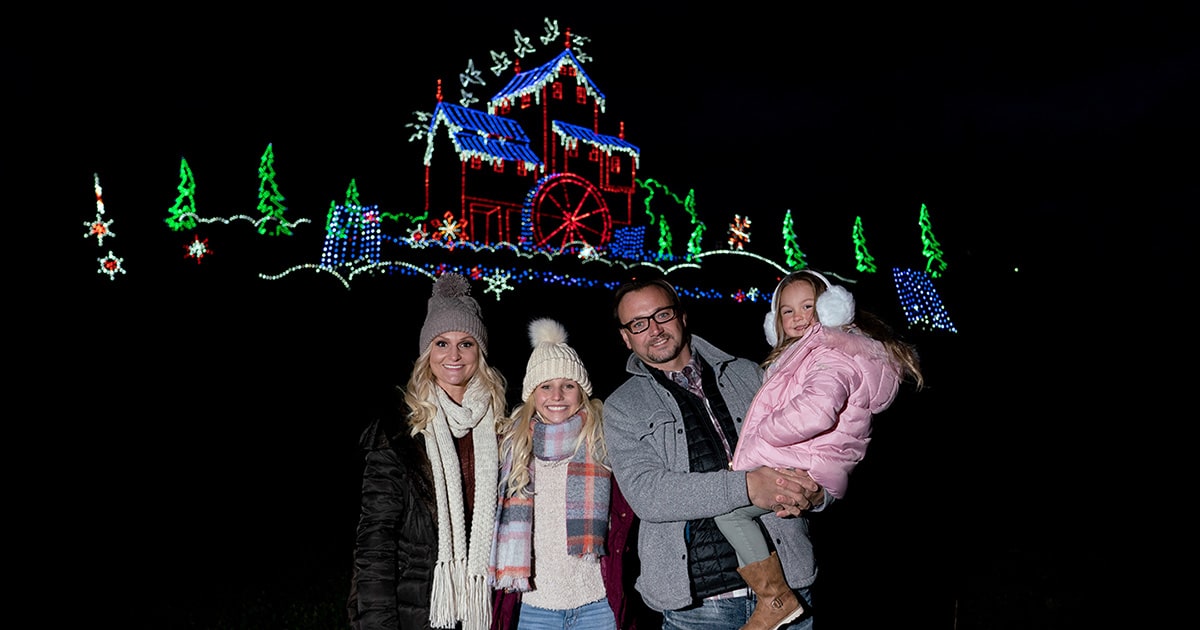 Winterfest Driving Tour of Lights - family posing in front of Old Mill light display
